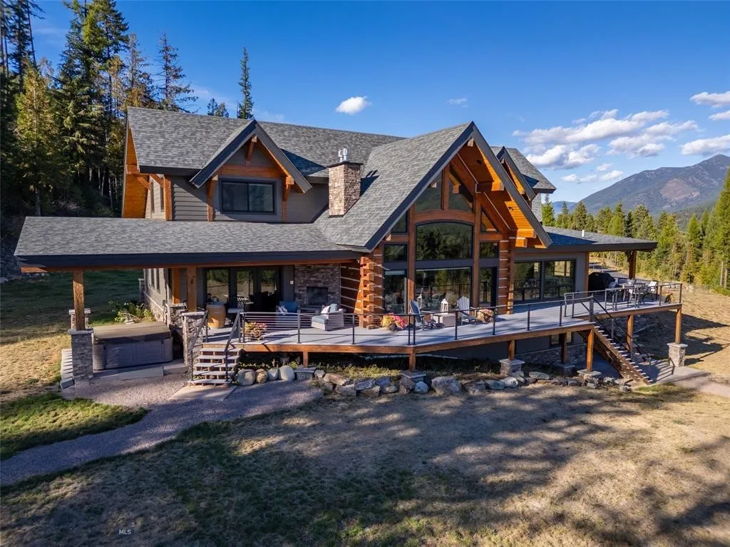 Back of house featuring stairway, a deck with mountain view, a shingled roof, and a chimney