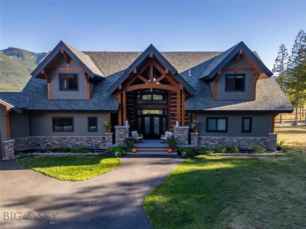 View of front of house with stone siding, french doors, roof with shingles, and a front yard
