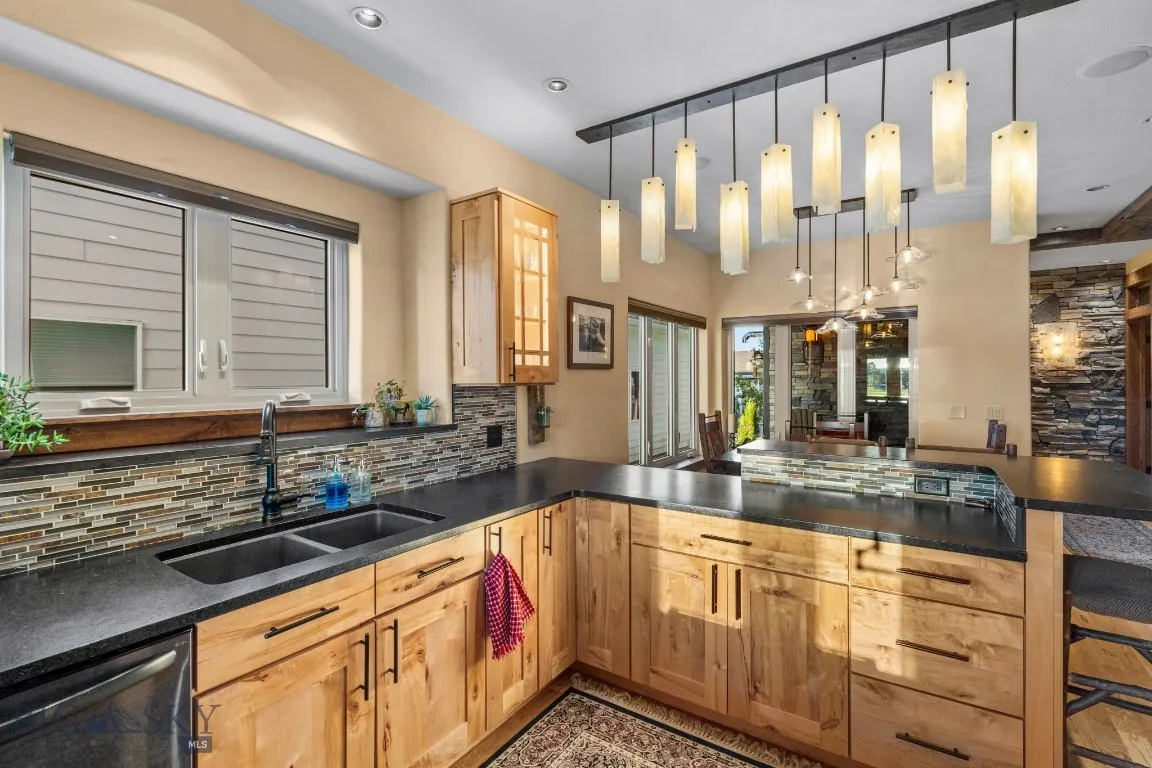 Kitchen featuring leathered granite countertops, black stainless appliances, and custom range hood