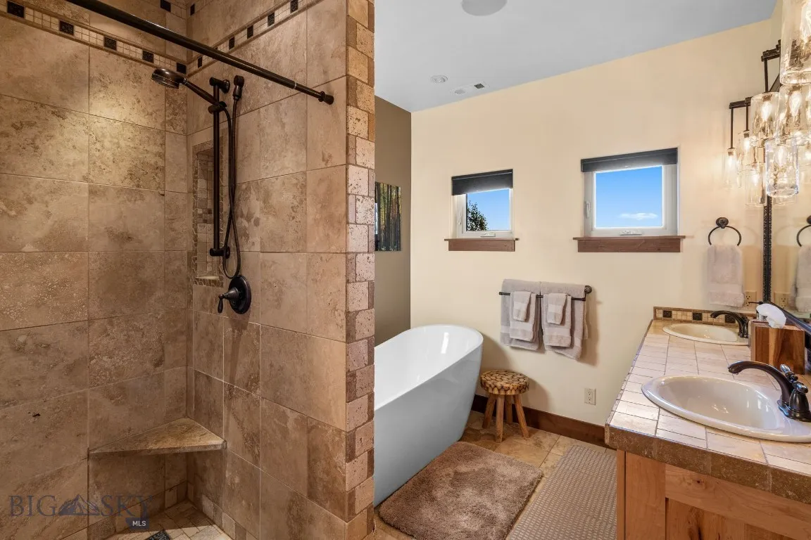 Primary bath with 6 shower head walk-in shower, heated floors, Montana Travertine tile, soaking tub and custom vanity by Ironglass