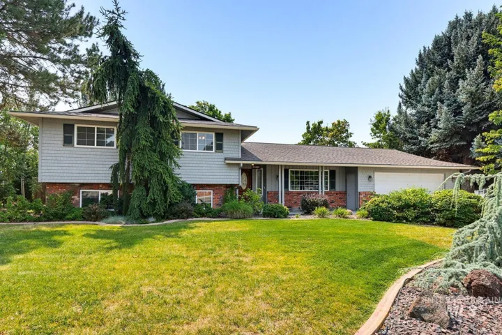 Split-level residence featuring brick and siding exterior, a two-car garage, and established landscaping