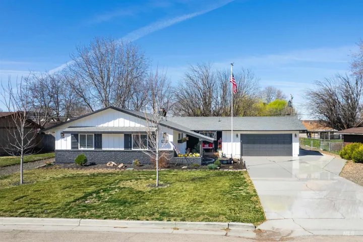 Ranch-style house with concrete driveway, an attached garage, a front lawn, a chimney, and board and batten siding