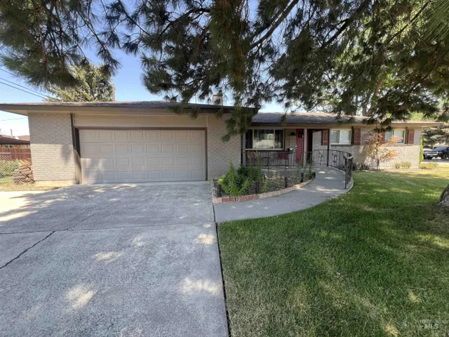 Ranch-style home featuring brick siding, an attached garage, a front yard, and concrete driveway