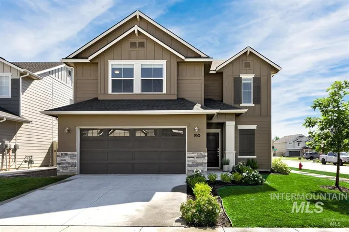 Two-story residence featuring a two-car garage, stone accent siding, covered entry, and a landscaped front yard with a concrete driveway