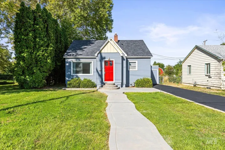 Exterior featuring blue siding, a vibrant red entry door, a gabled roof, a paved driveway, and a concrete walkway