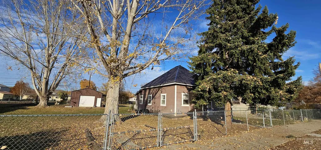 View of property exterior with a fenced front yard, a gate, and an outbuilding