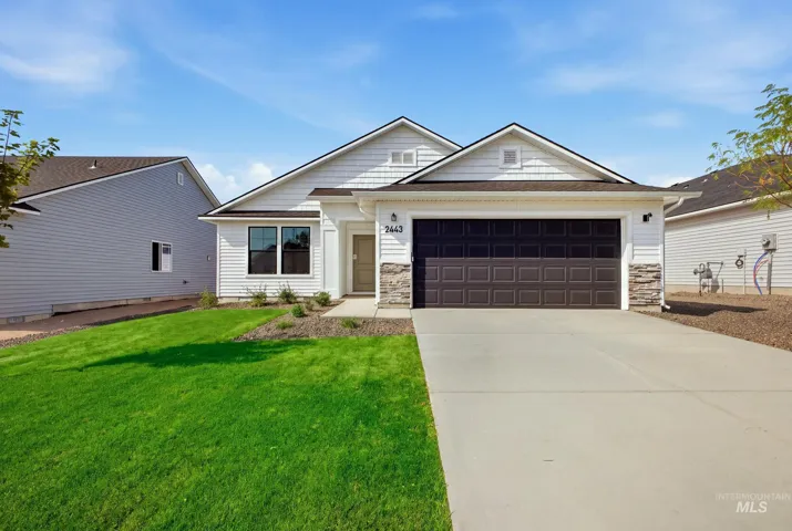 White horizontal siding exterior with dark-paneled garage door, stone veneer accents, and a concrete driveway