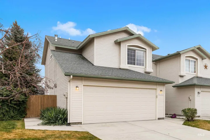 Traditional-style home featuring a shingled roof, driveway, and an attached garage