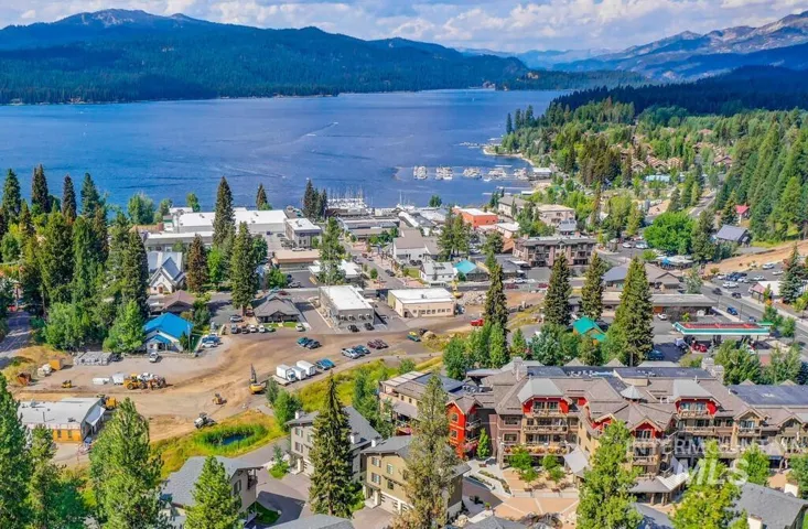 Aerial perspective showcasing a multi-story lodge with stone and timber-style siding, pitched rooflines, and mountain and lake scenery