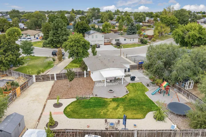 Expansive backyard featuring a covered patio, paved hardscaping, a manicured lawn, and perimeter fencing