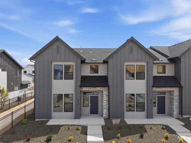 Contemporary townhome exterior featuring board and batten siding, stone accents, and a dark asphalt shingle roof
