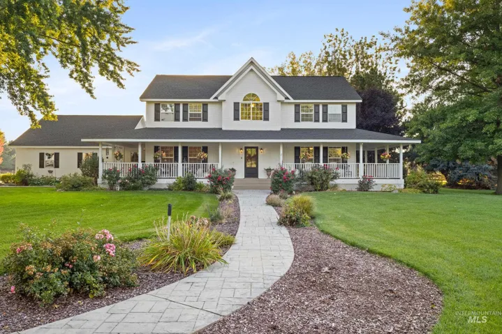 Two-story residence with a white exterior, featuring a full-width front porch with white railings, a gray shingle roof, and dark shutters