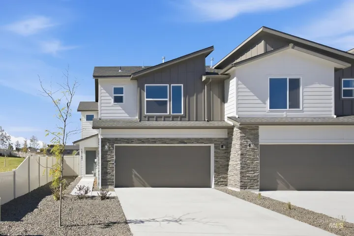 Contemporary exterior featuring white horizontal siding, gray vertical siding, stacked stone accents, a concrete driveway, and an attached garage
