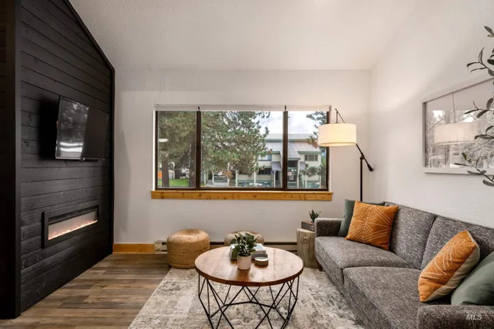 Living area featuring a floor-to-ceiling accent wall with horizontal wood paneling and a linear electric fireplace