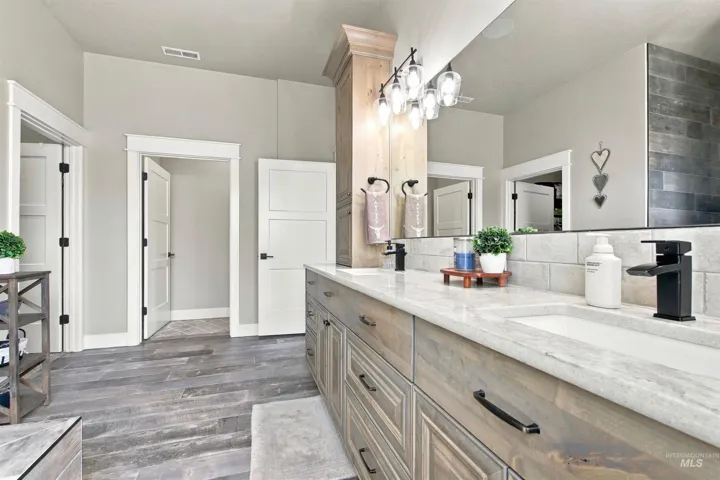 Dual vanity with integrated sinks, wood-finish cabinetry, quartz countertops, and matte black fixtures
