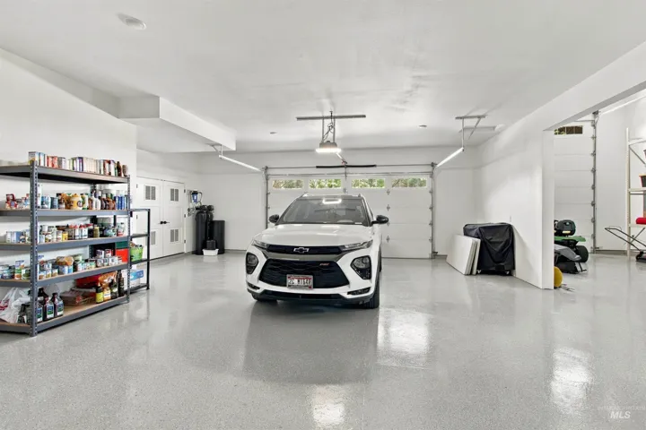 Spacious garage with light gray speckled flooring, two overhead garage doors, and recessed ceiling lighting