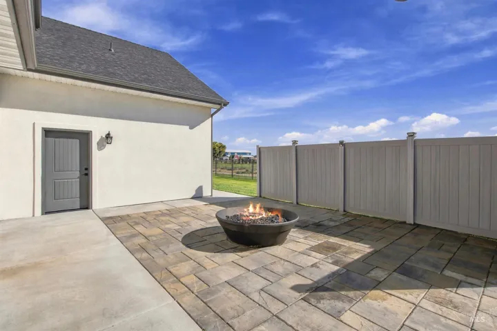 Concrete patio with an integrated paver section, a built-in fire pit, and a privacy fence