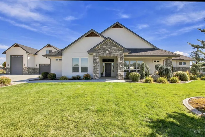 Modern stucco exterior with stone accents, a covered entry, and multiple garage doors
