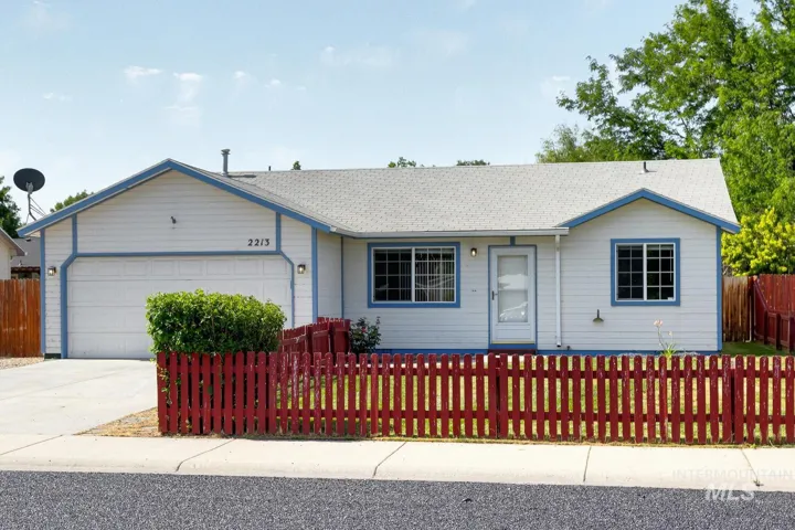 Ranch-style home with an attached garage, a fenced front yard, driveway, and a shingled roof