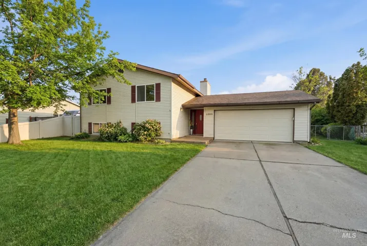 Split level home featuring a garage, driveway, and a chimney