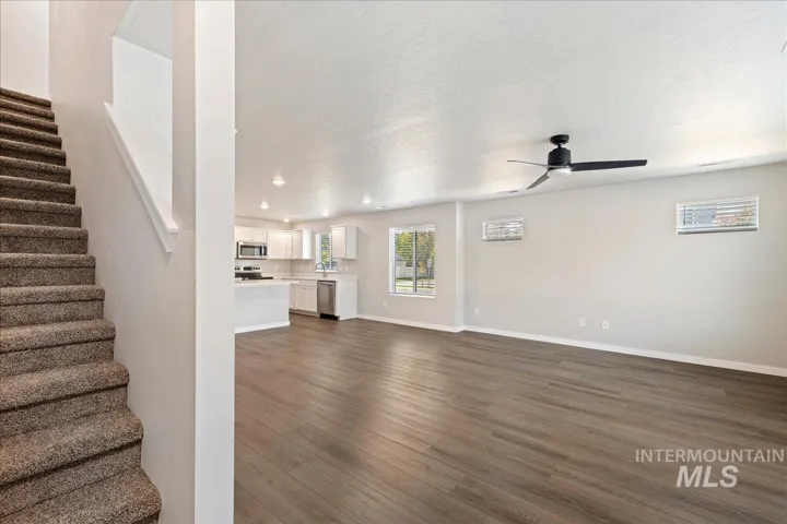 Open-concept interior featuring wood-finish flooring, recessed lighting, a modern ceiling fan, and staircase with carpeted treads