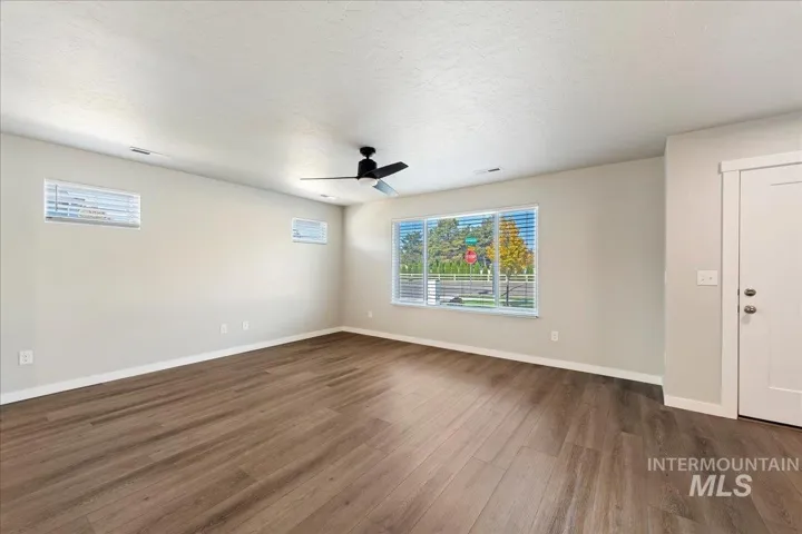 Interior space featuring wood-finish flooring, a multi-pane window, two smaller horizontal windows, and a ceiling-mounted fan with light fixture