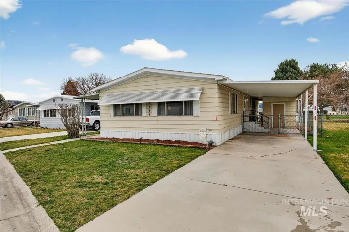 Manufactured / mobile home with concrete driveway, a carport, a gate, and a porch