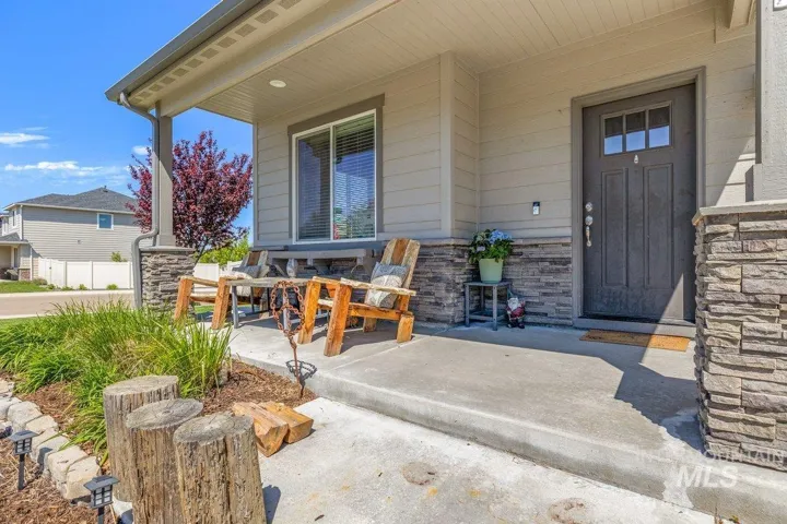Covered front porch featuring stacked stone accents, horizontal siding, and a dark entry door with upper window panes