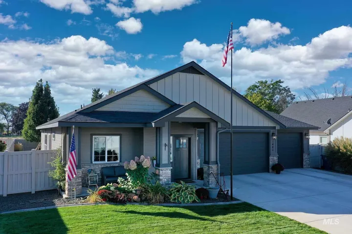 Contemporary single-story residence with a two-car garage, concrete driveway, and a front yard featuring a manicured lawn and mature landscaping