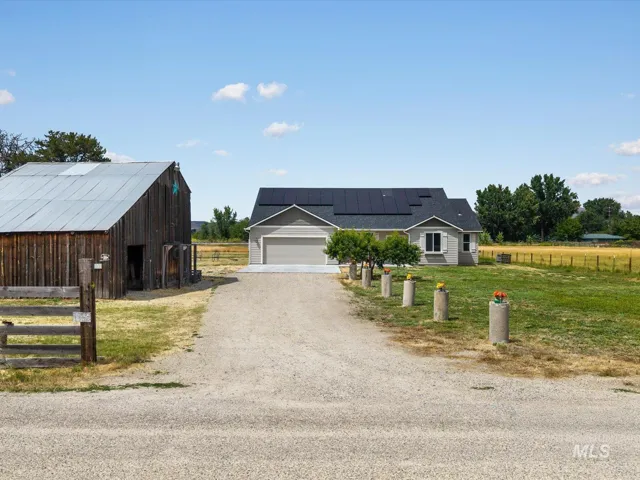 Property featuring a light gray exterior with dark roof, solar panels, and an attached two-car garage