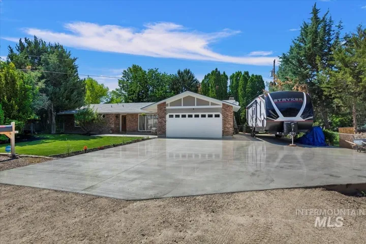Ranch-style house with driveway, a front lawn, brick siding, a garage, and a chimney