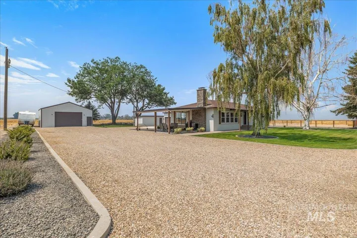 Ranch-style residence featuring a stone chimney and an attached covered patio