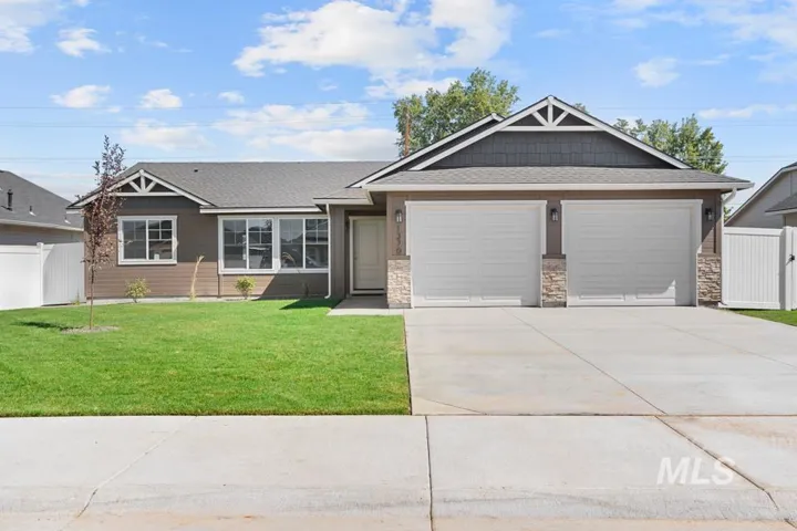 Single-story residence featuring a two-car garage with stone accents, a concrete driveway, and a front lawn