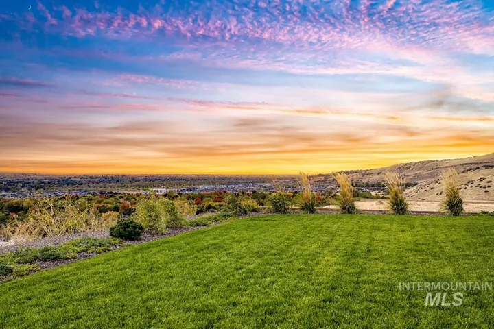Expansive backyard featuring a manicured lawn, tiered landscaping, ornamental grasses, and a mountain backdrop