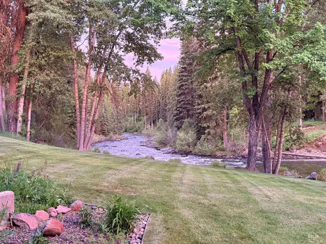 Expansive lawn with mature trees and a natural river boundary