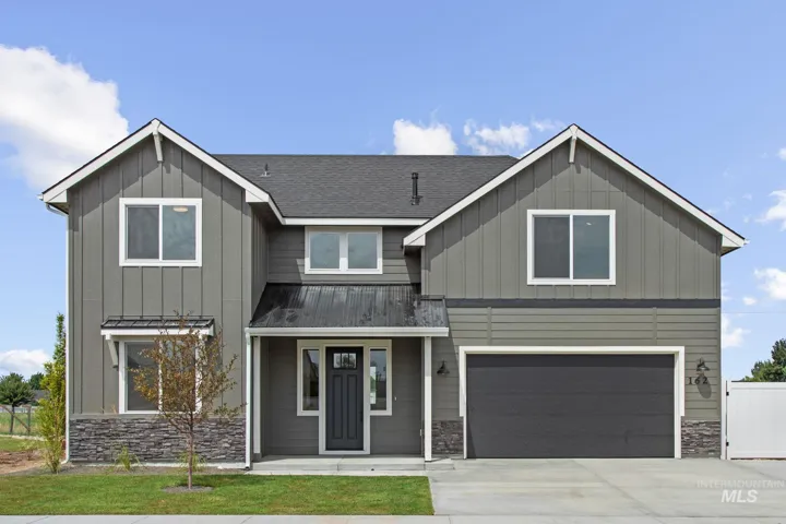 Two-story residence featuring a dark gray siding exterior, stone veneer accents, an attached two-car garage, a covered front porch, and a dark asphalt shingle roof