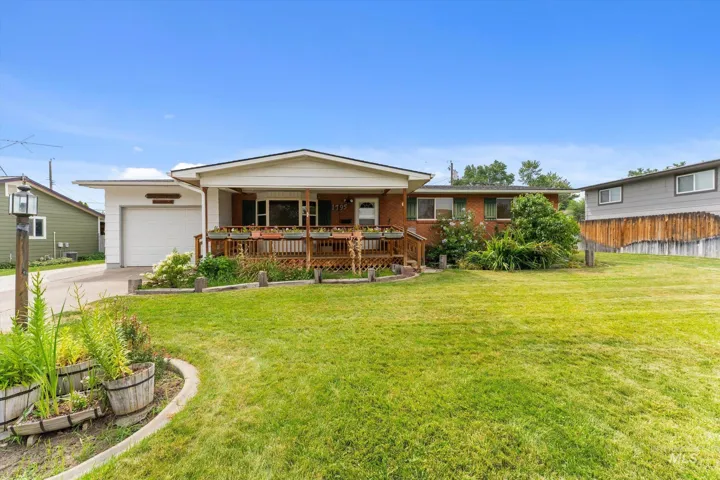 Ranch-style residence featuring a prominent front porch with wood railing and a spacious front lawn