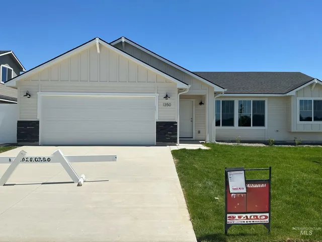 Single story home featuring board and batten siding, a front lawn, a garage, driveway, and stone siding