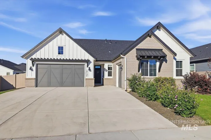 Contemporary exterior with white board and batten siding, light brick accents, dark roof, and a two-car garage with a gray door