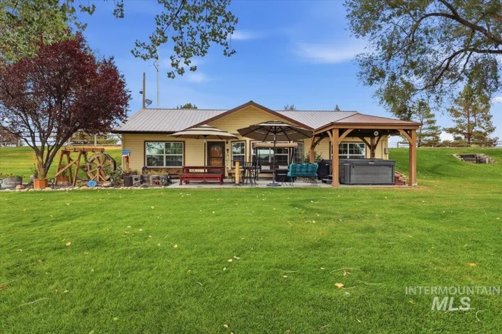 Expansive green lawn with a covered patio, separate wooden pergola, and metal roofing