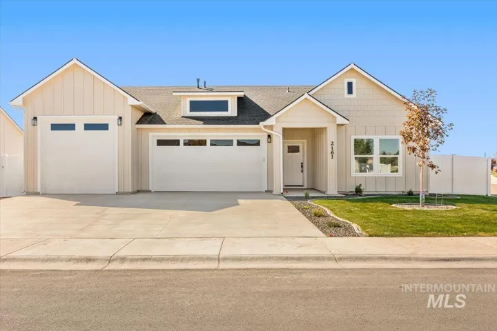 View of front of property with a shingled roof, board and batten siding, driveway, and a garage