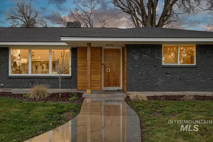 View of front of house featuring a yard, a shingled roof, and brick siding