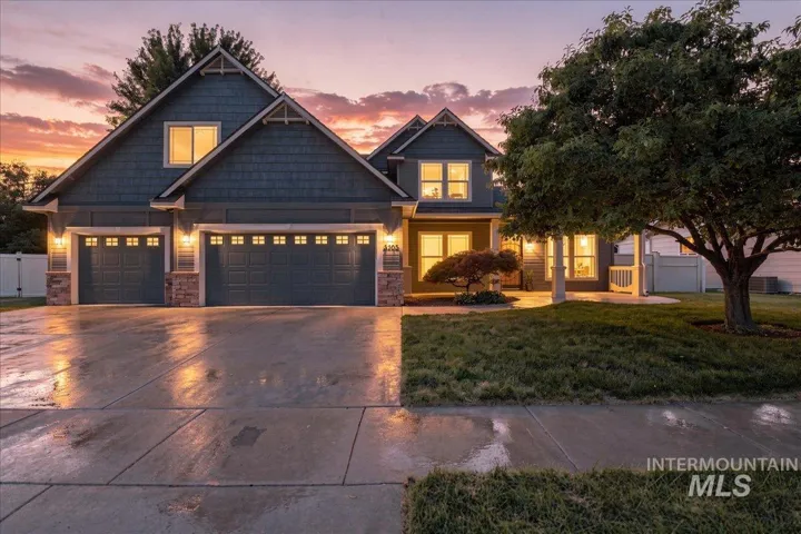 Two-story residence featuring a two-car garage with individual doors, stone facade accents, and a covered front porch