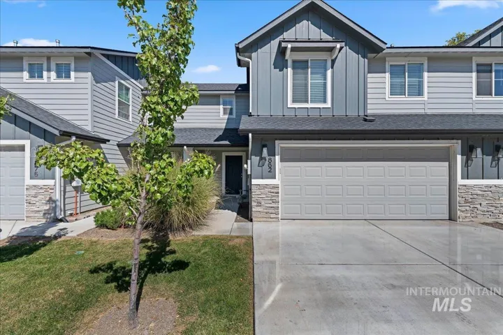Modern residential exterior featuring vertical and horizontal siding, stone accents, a two-car garage, and a concrete driveway