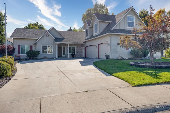 Elegant two-story residence featuring a concrete driveway with clean geometric divisions, two-car attached garage, and mixed exterior materials including fiber cement siding and stone accents
