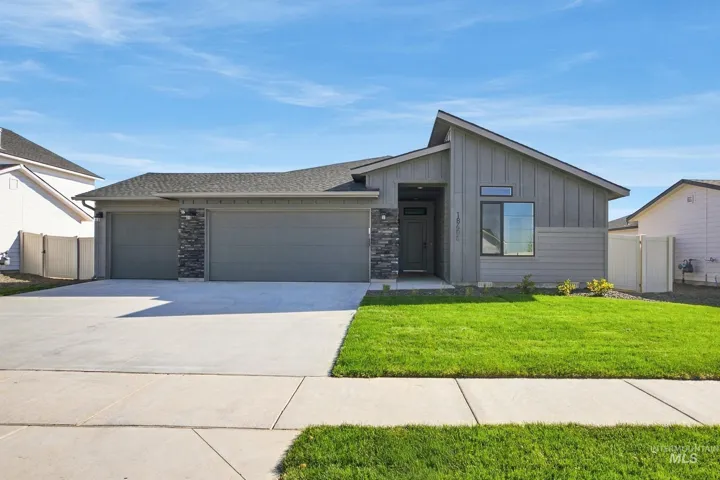 Modern ranch-style exterior featuring vertical and horizontal siding, stone veneer accents, a three-car garage, and a covered entryway
