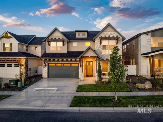 Two-story residence featuring stone and siding exterior, a two-car garage, and a covered front entry