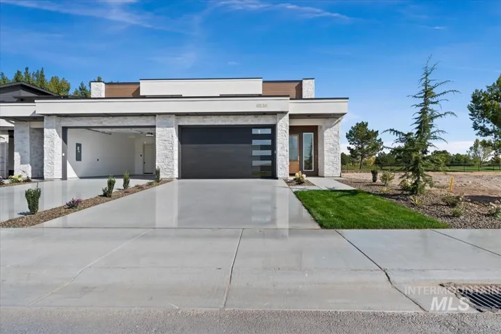 Contemporary exterior with stone veneer accents, flat roofline, integrated two-car garage, and a wood-finish front door with sidelights