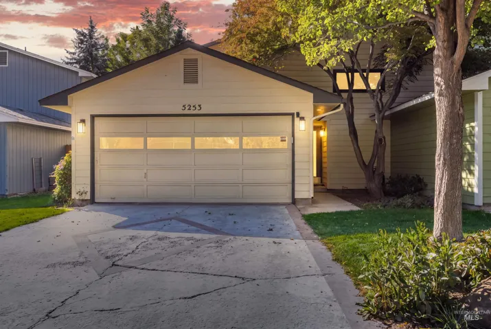 Attached garage featuring a paneled door with upper glass inserts, dual exterior sconce lighting, and a paved driveway