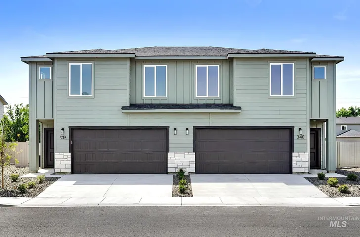 Contemporary duplex exterior featuring light green siding, dark garage doors, and white stone accents